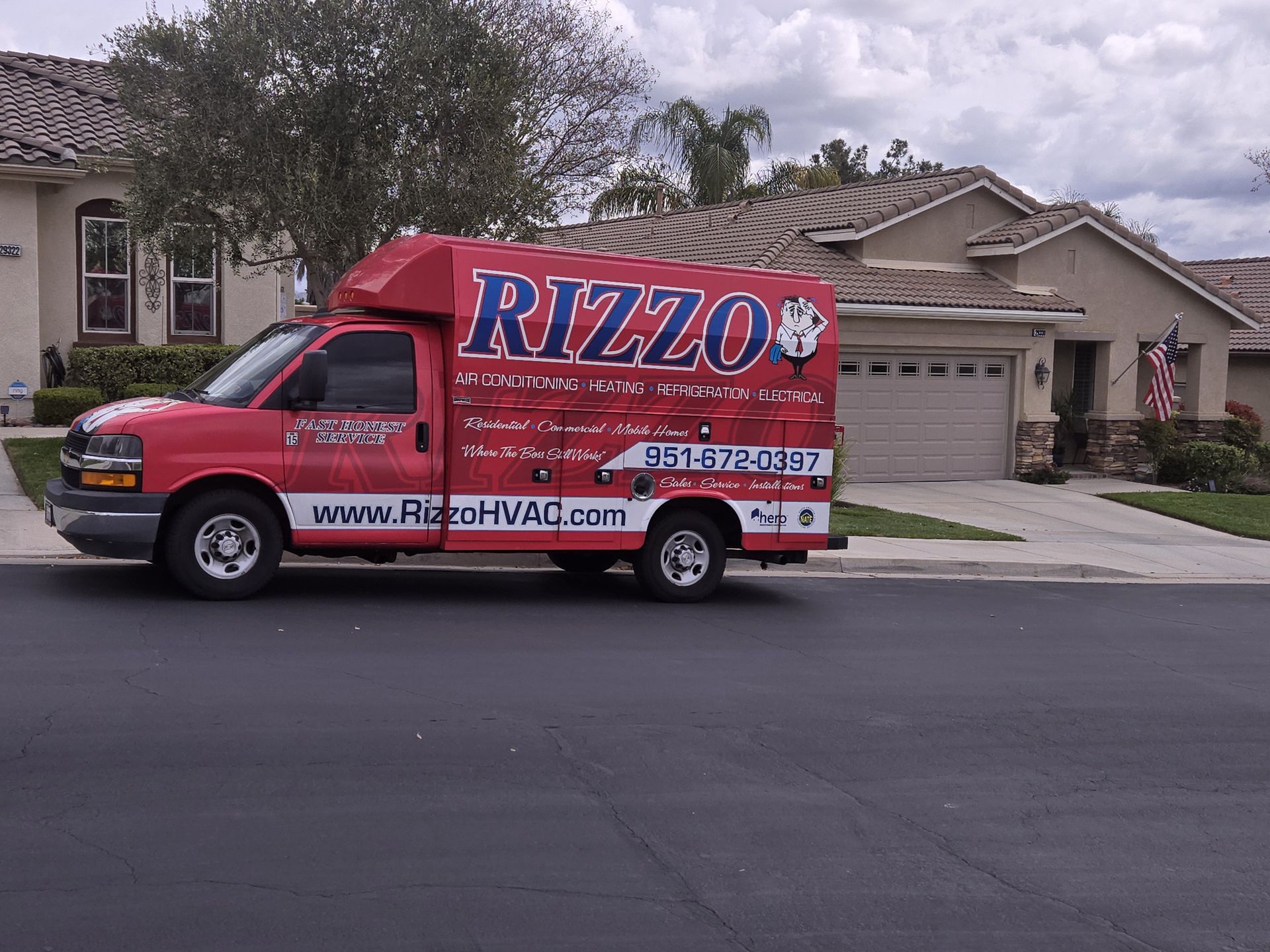 A red Rizzo box truck with the full company wrap parked in front of a Temecula Valley home